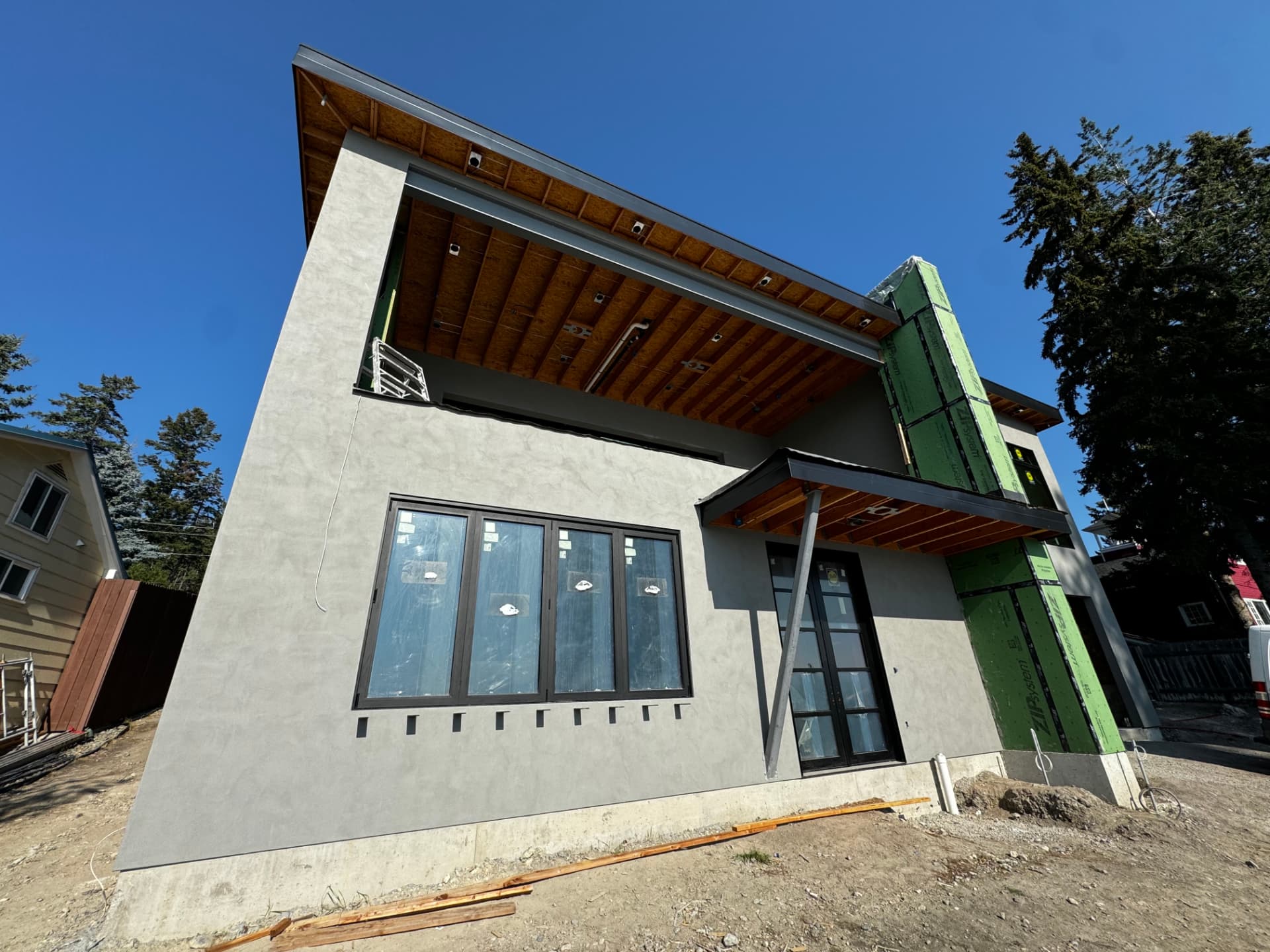 Smooth grey stucco exterior with deep timber soffits on a modern home in Kalispell, Montana