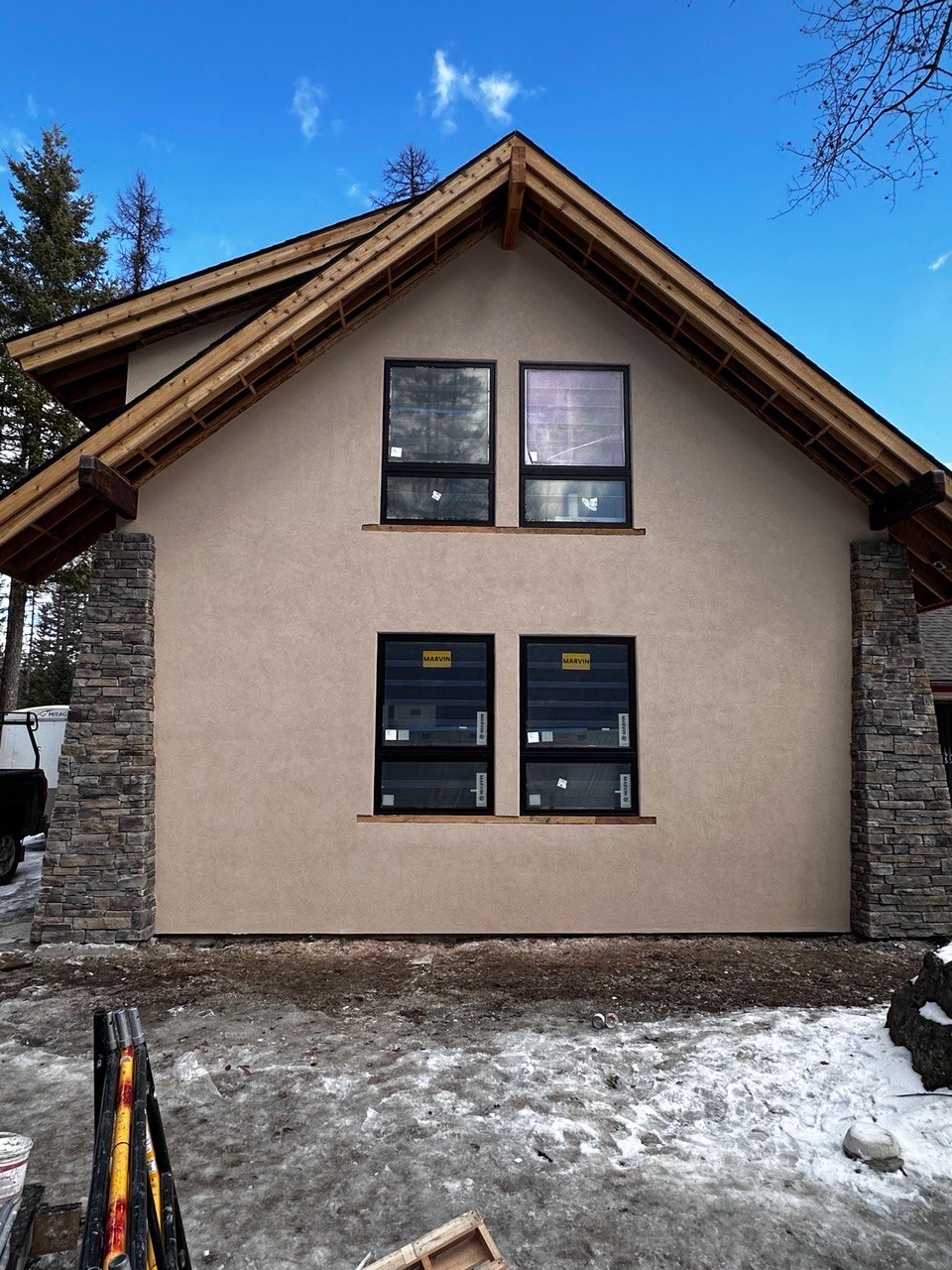 Stucco gable with stone veneer columns and timber eaves on a home near Bigfork, Montana