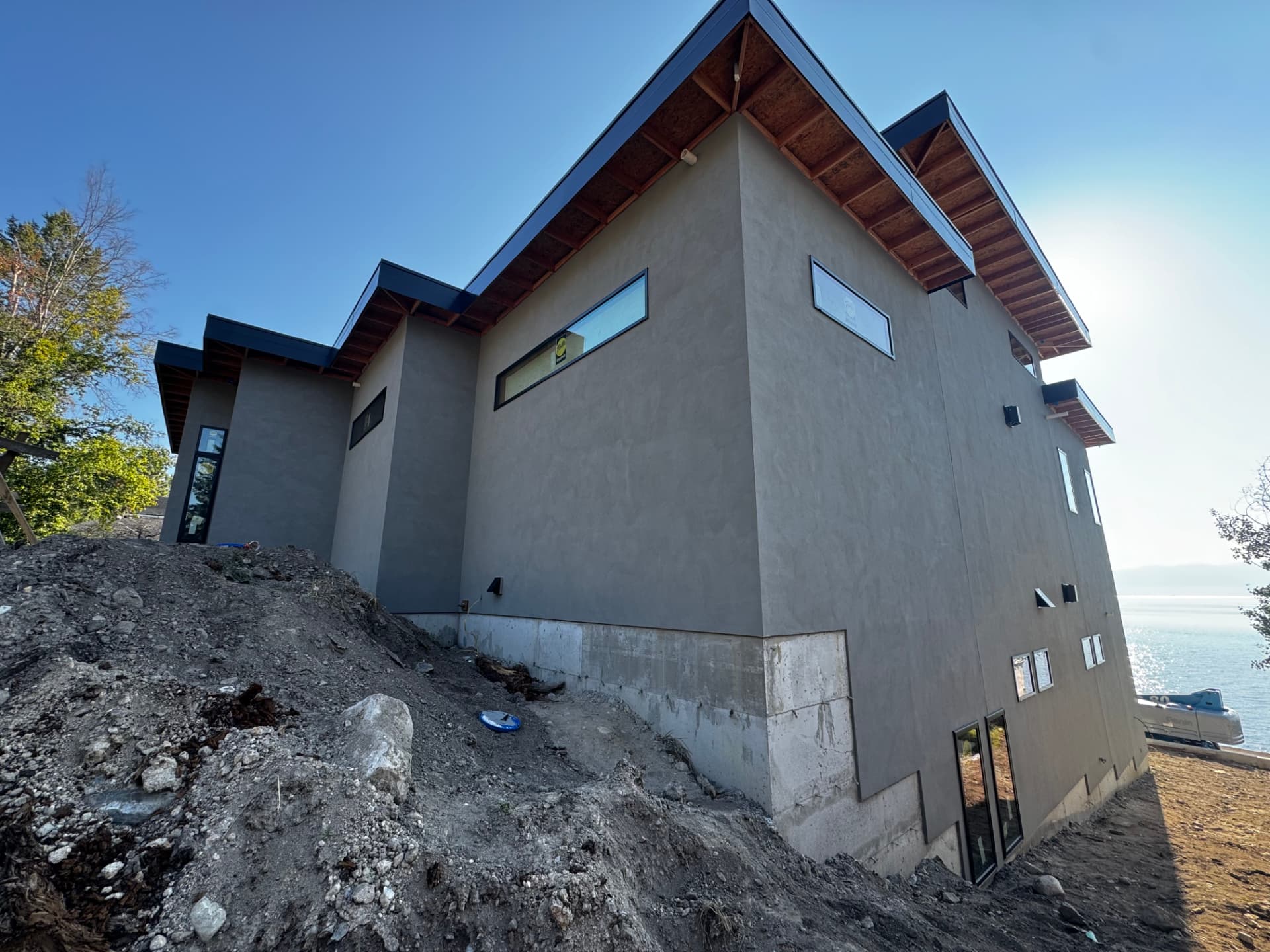 White stucco lakeside home exterior with stone veneer base in Lakeside, MT